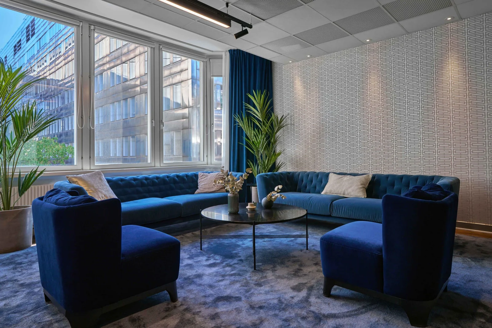 Blue sofas and a shared lounge beside the windows at United Spaces, Drottninggatan 33