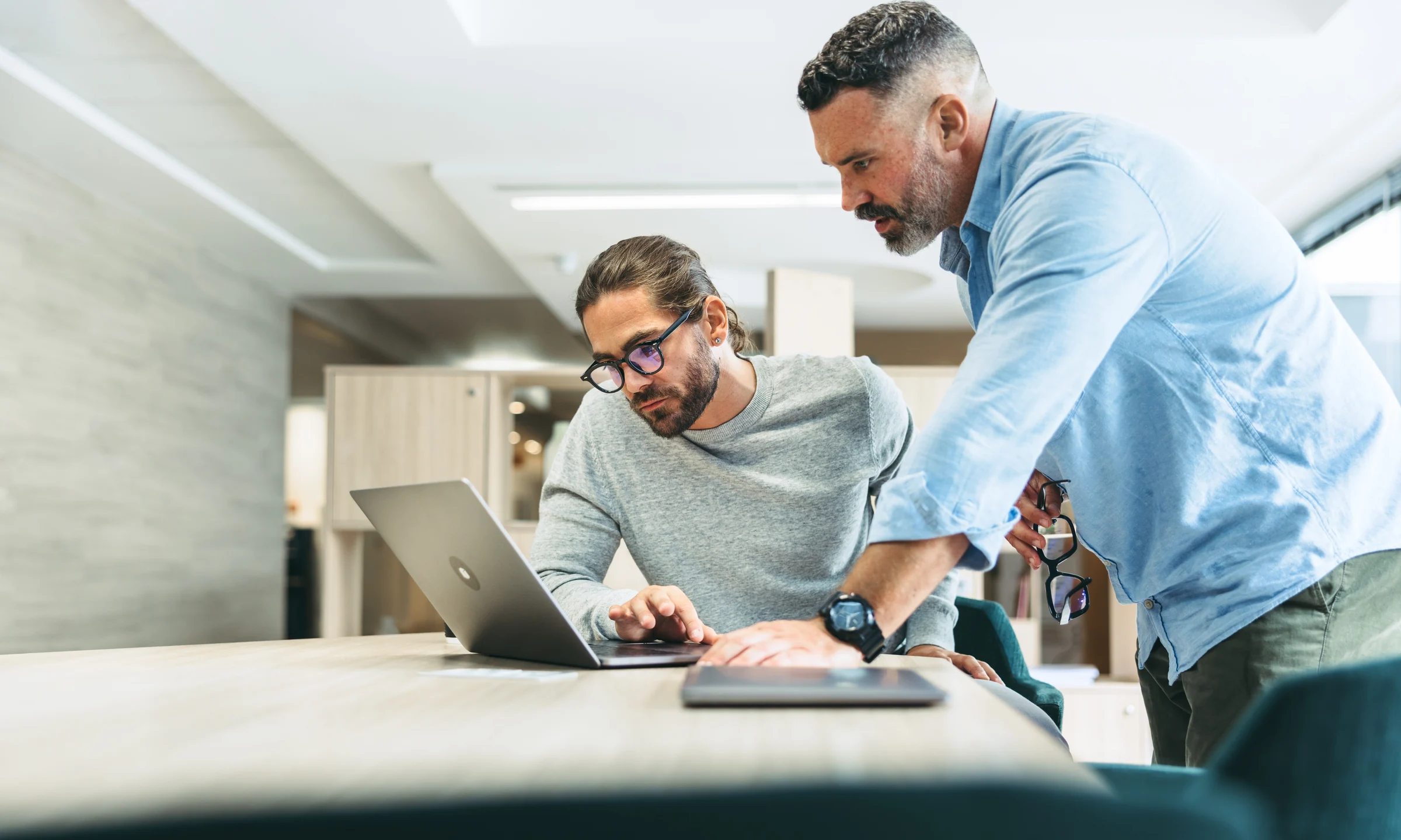 Two colleagues reviewing information together on a laptop at a workstation.