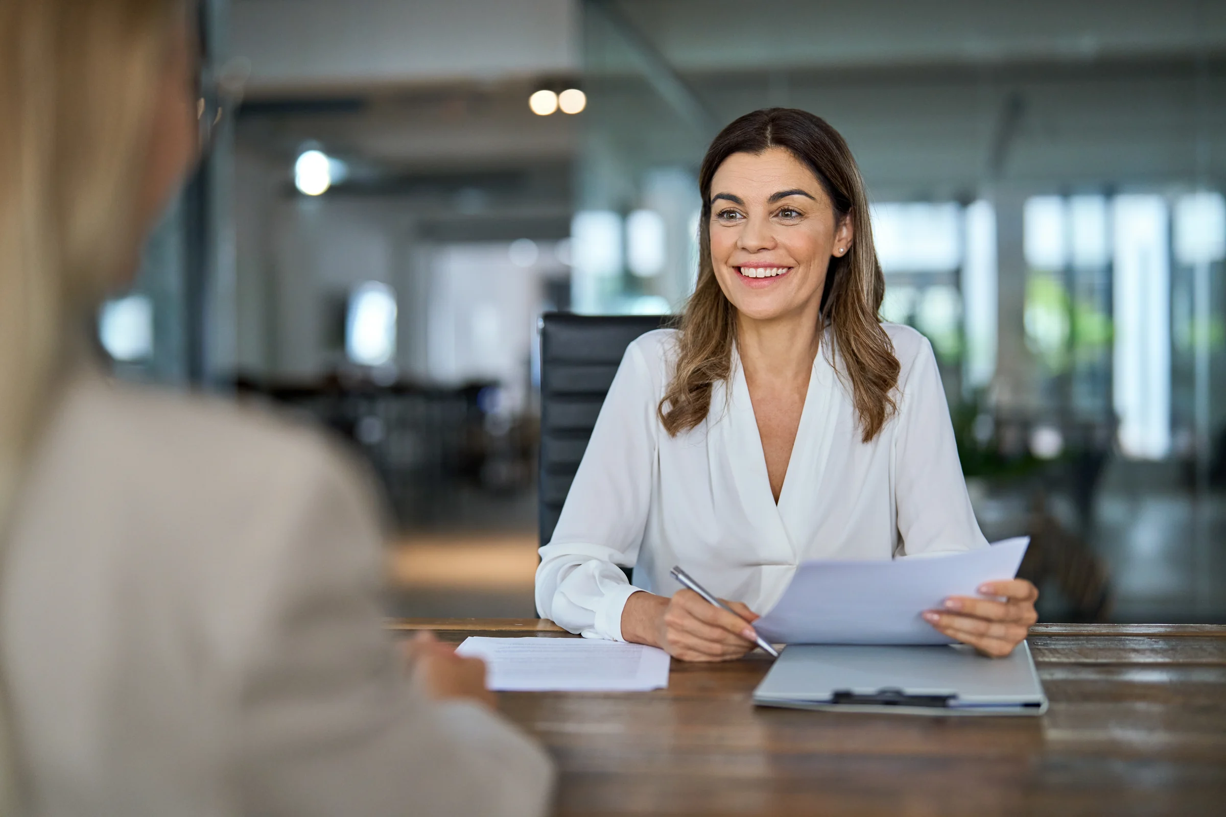 A professional discussing paperwork with a colleague across a meeting table.