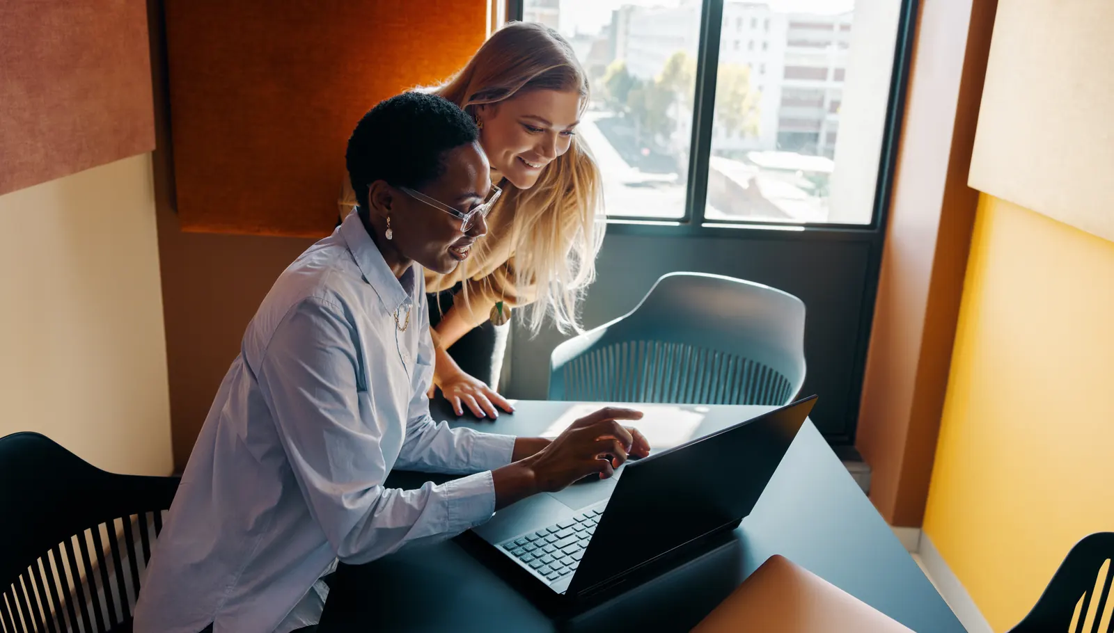 Two specialists reviewing documents and a laptop in a quiet workspace