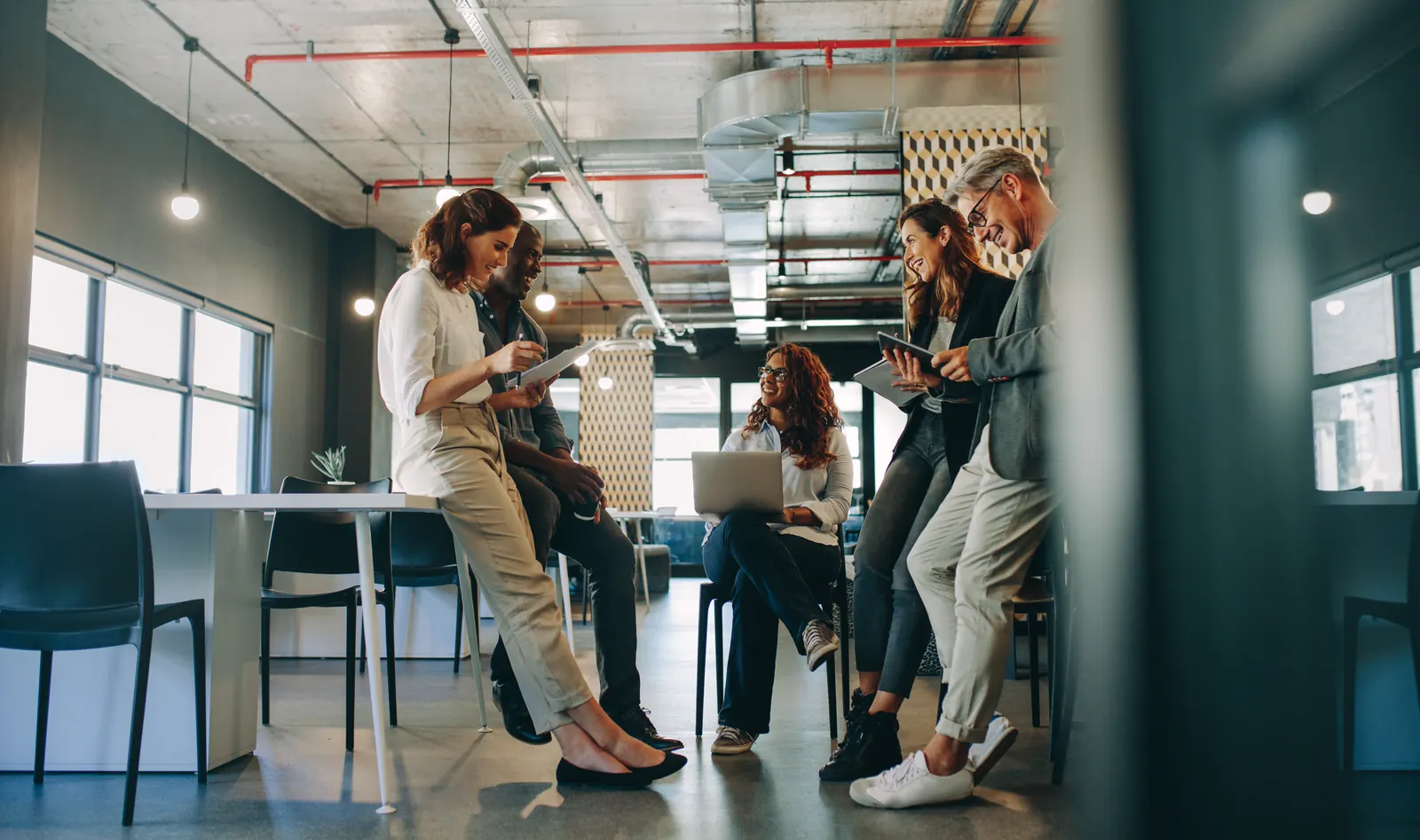 Colleagues gathered around high tables with a laptop and notes in an open office