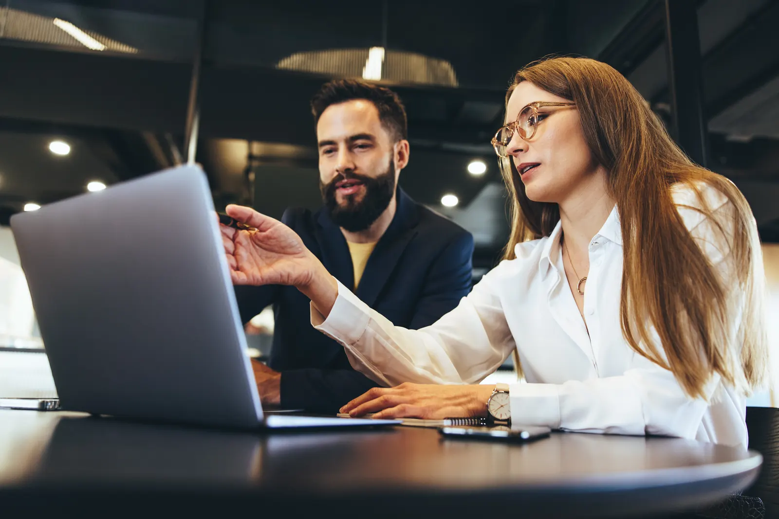 Two colleagues examining information together on a laptop