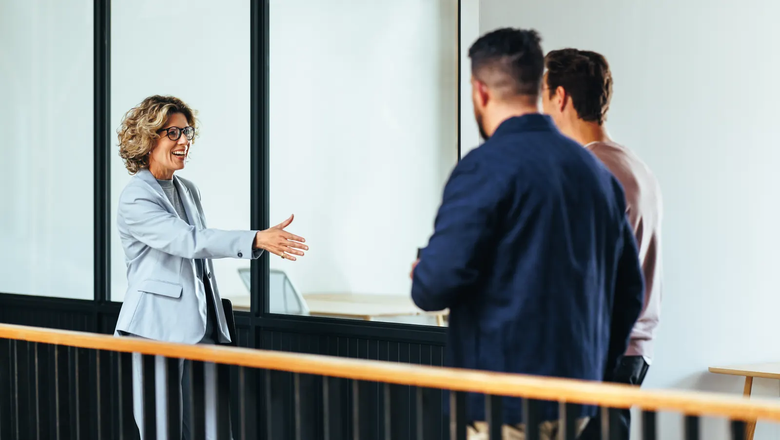 Illustrative stock photograph of professionals greeting one another on an office mezzanine