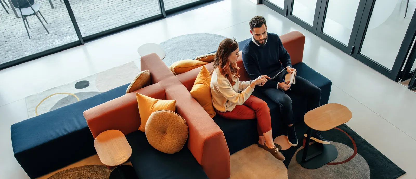An overhead view of colleagues discussing work on an orange sofa