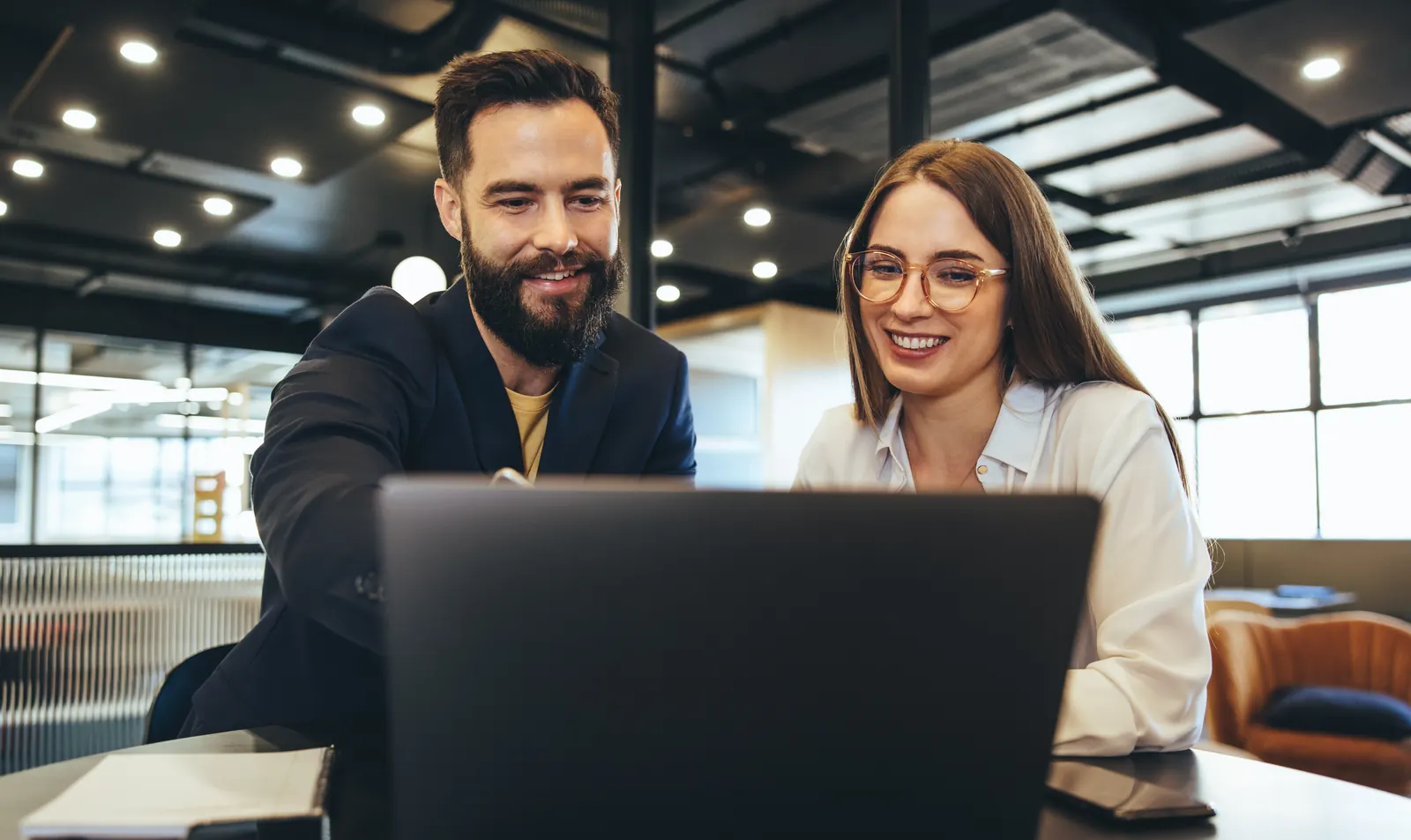 Two colleagues examining information on the same laptop