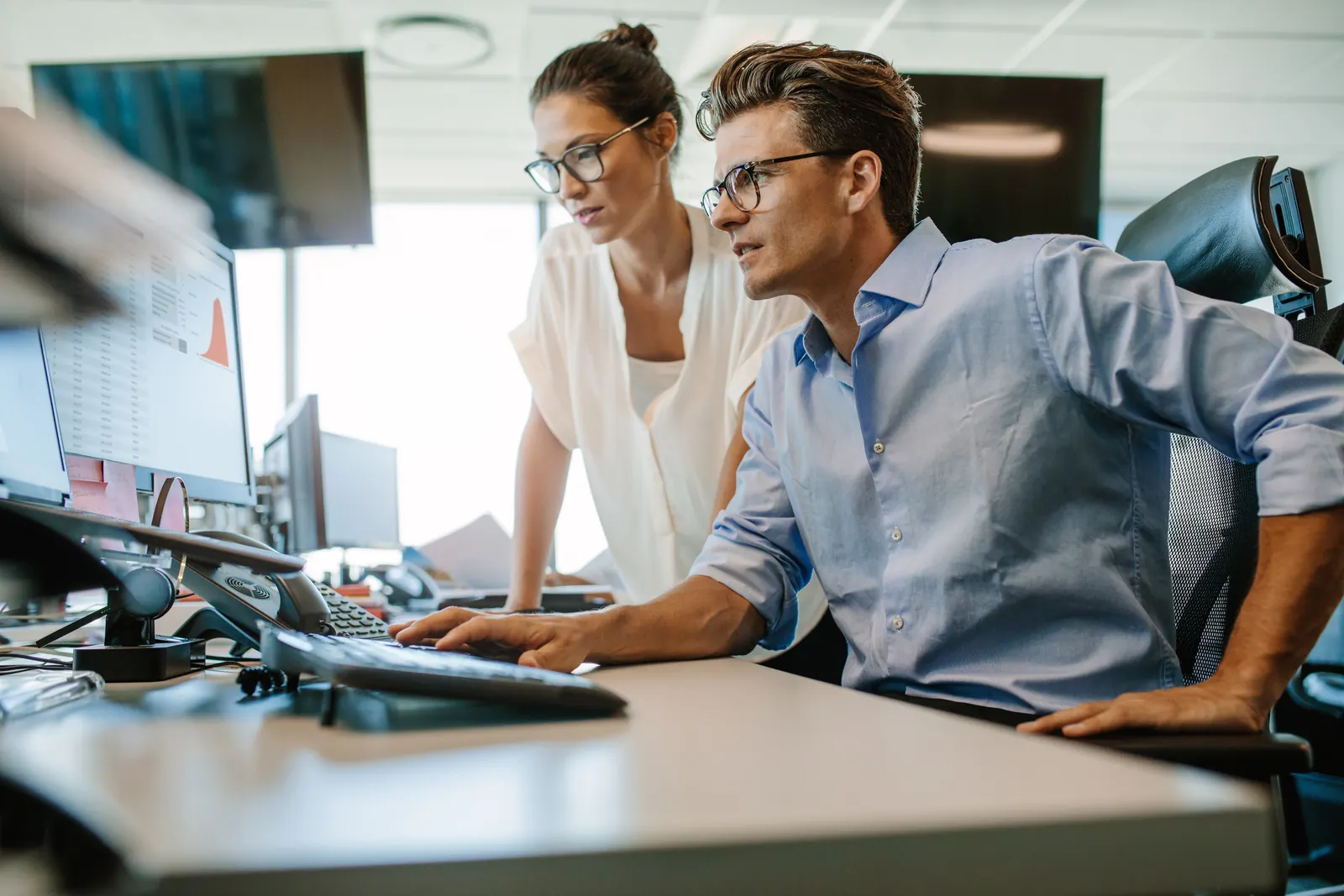 Two specialists reviewing work on a desktop display