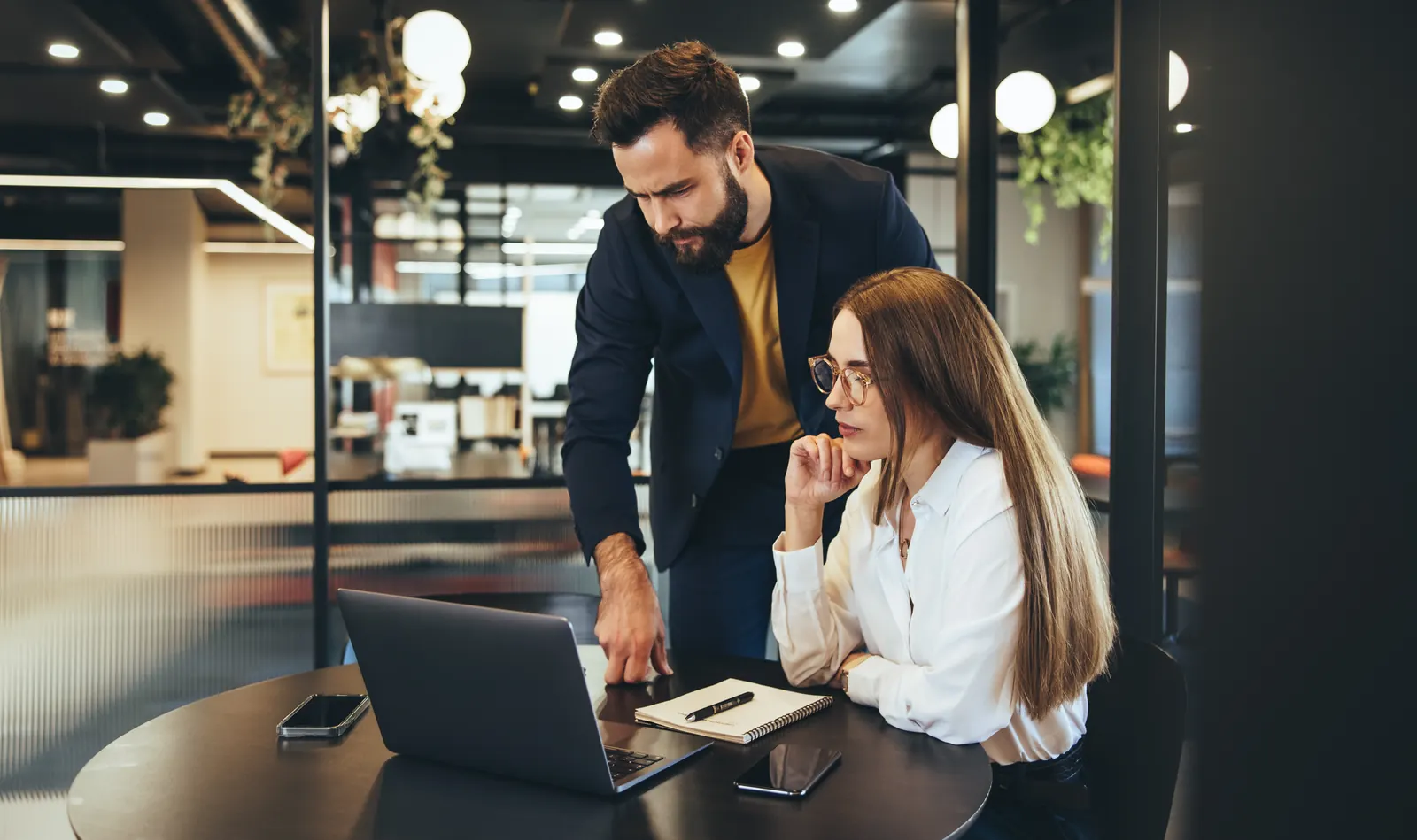 Two colleagues reviewing information together at a laptop in an office