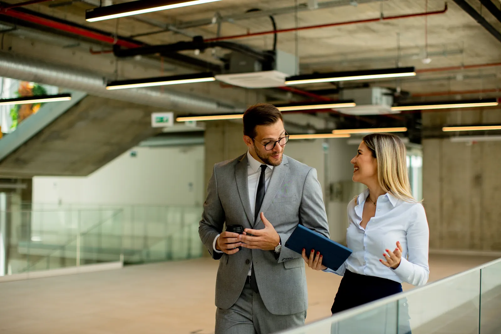 Two project professionals walking together in a modern building