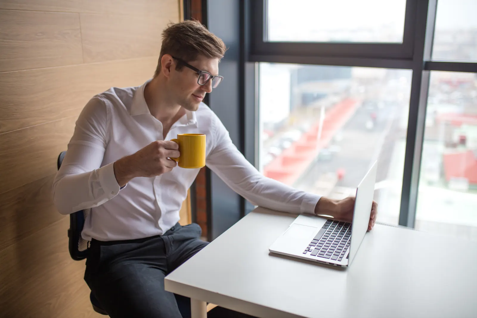 A professional checking information on a laptop beside a window