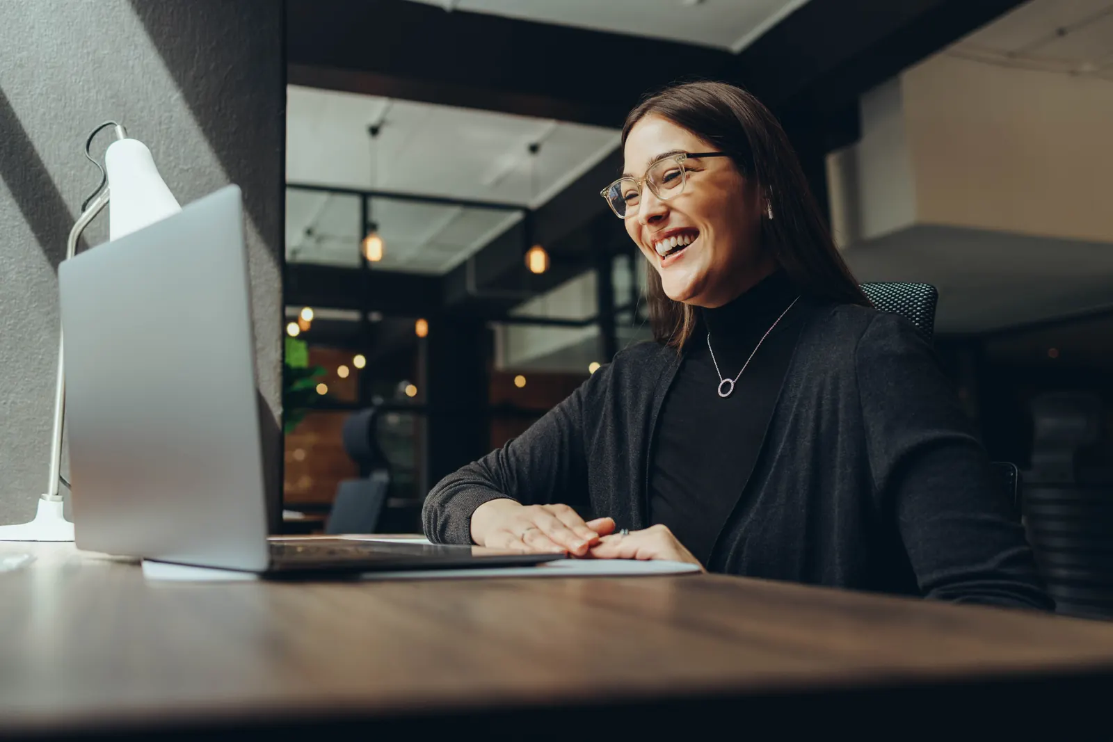 A smiling professional working on a laptop in a shared workspace