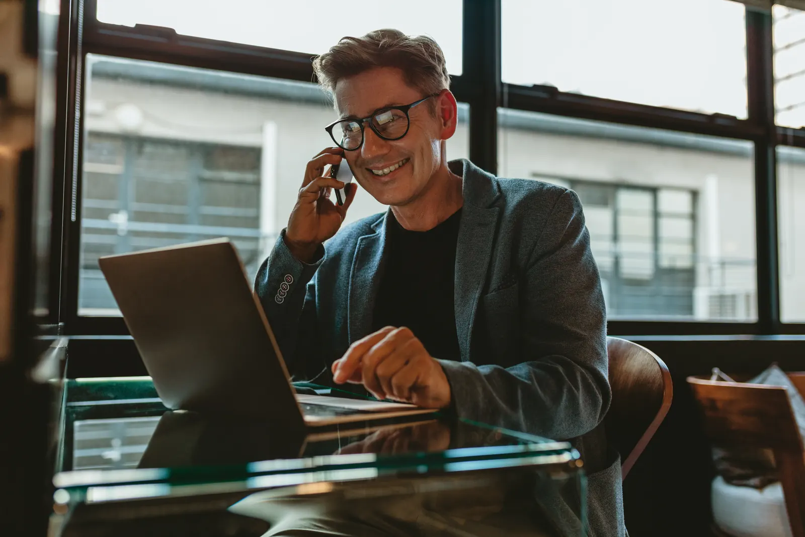 An account professional speaking on a phone beside an open laptop at a desk