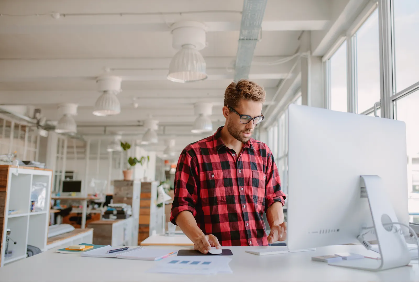Specialist working at a large desktop display in a bright office