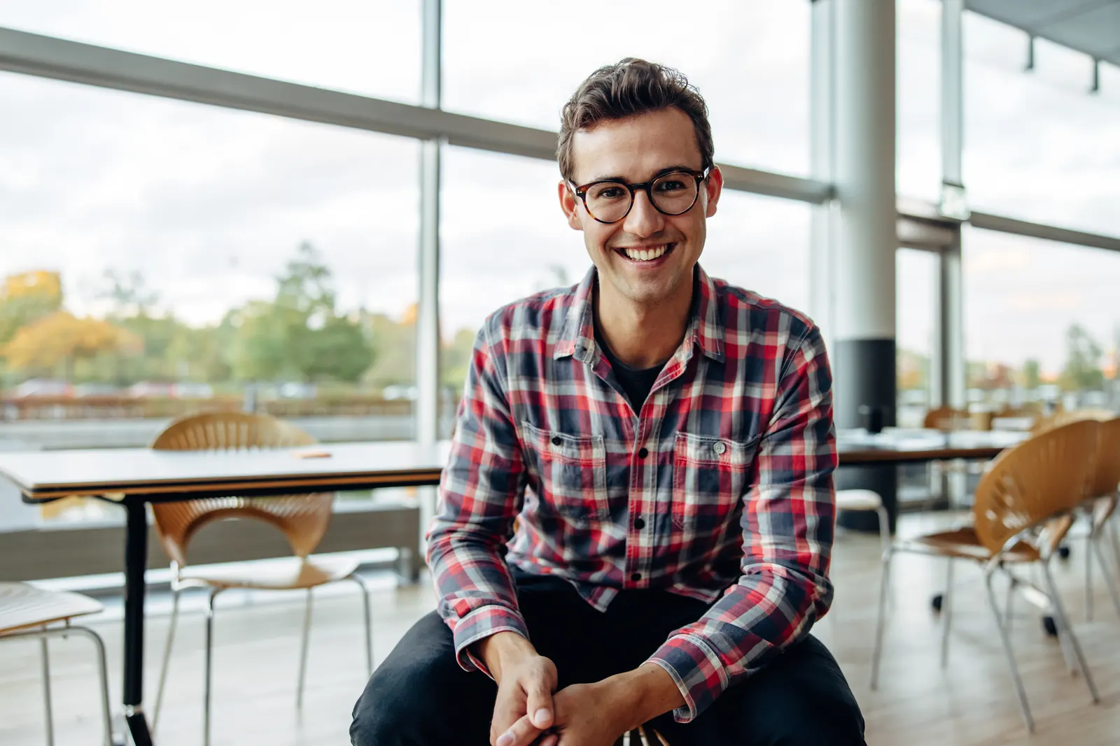 A small-business professional in a checked shirt seated at an office desk