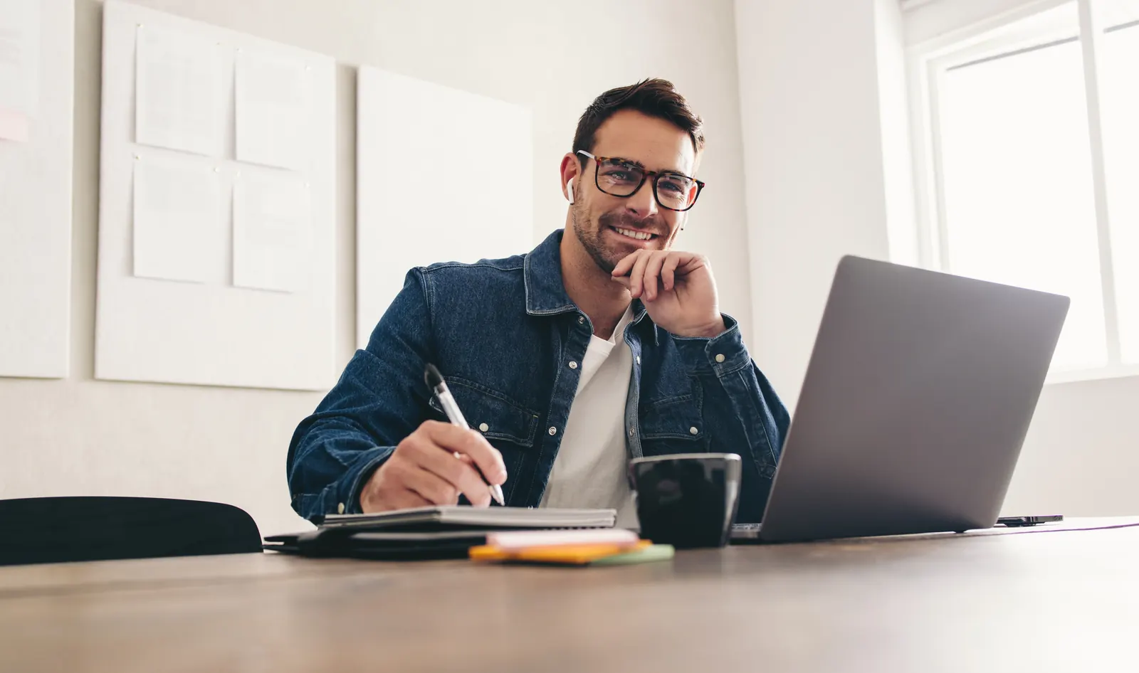 A business analyst comparing notes and information beside an open laptop