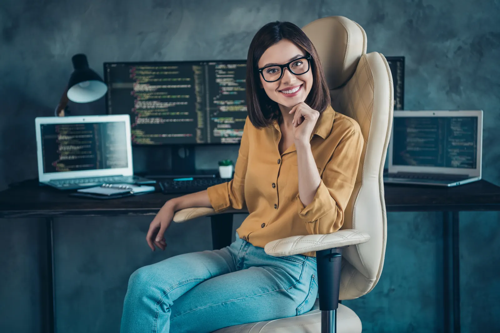 A data professional with glasses working beside several monitors in a studio