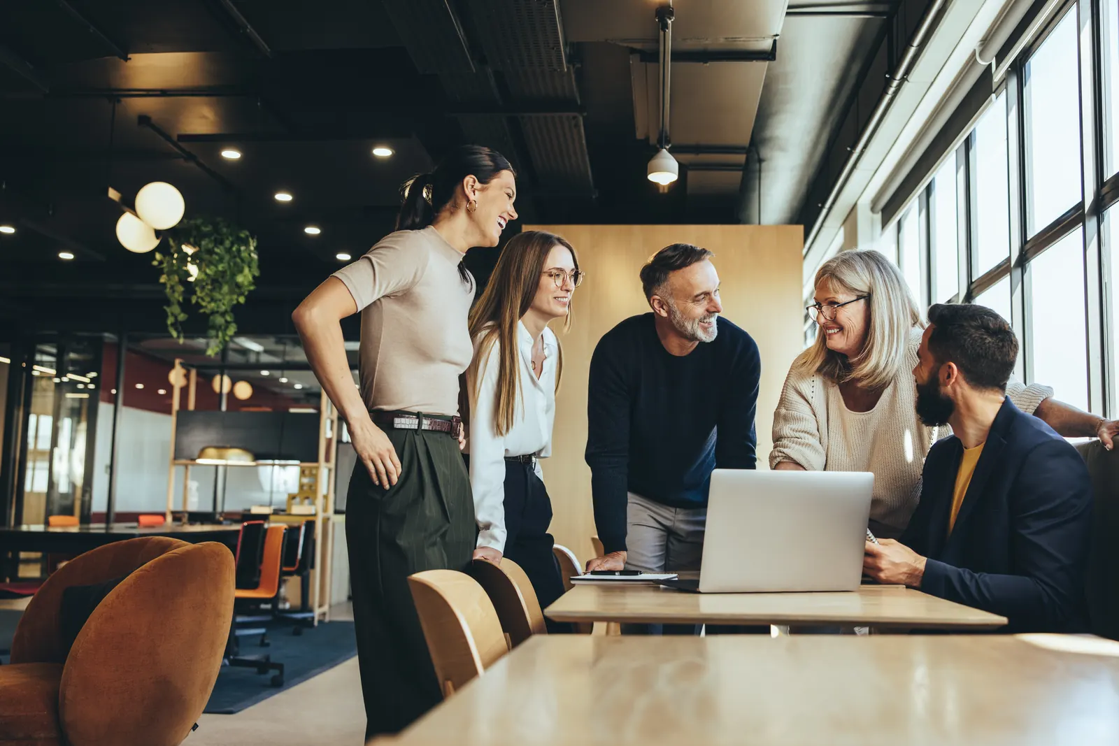 Sales colleagues reviewing a shared laptop around a meeting table