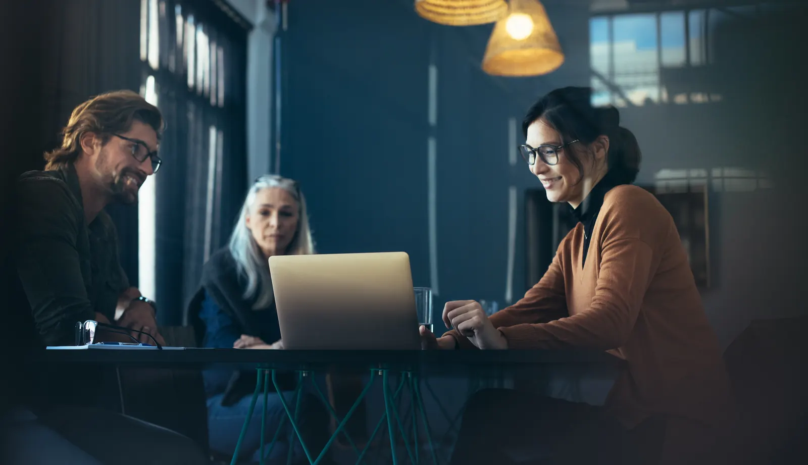 Three project colleagues reviewing work together around a laptop