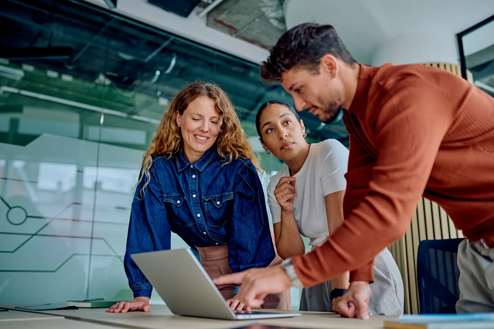 Three colleagues checking a task together on a laptop