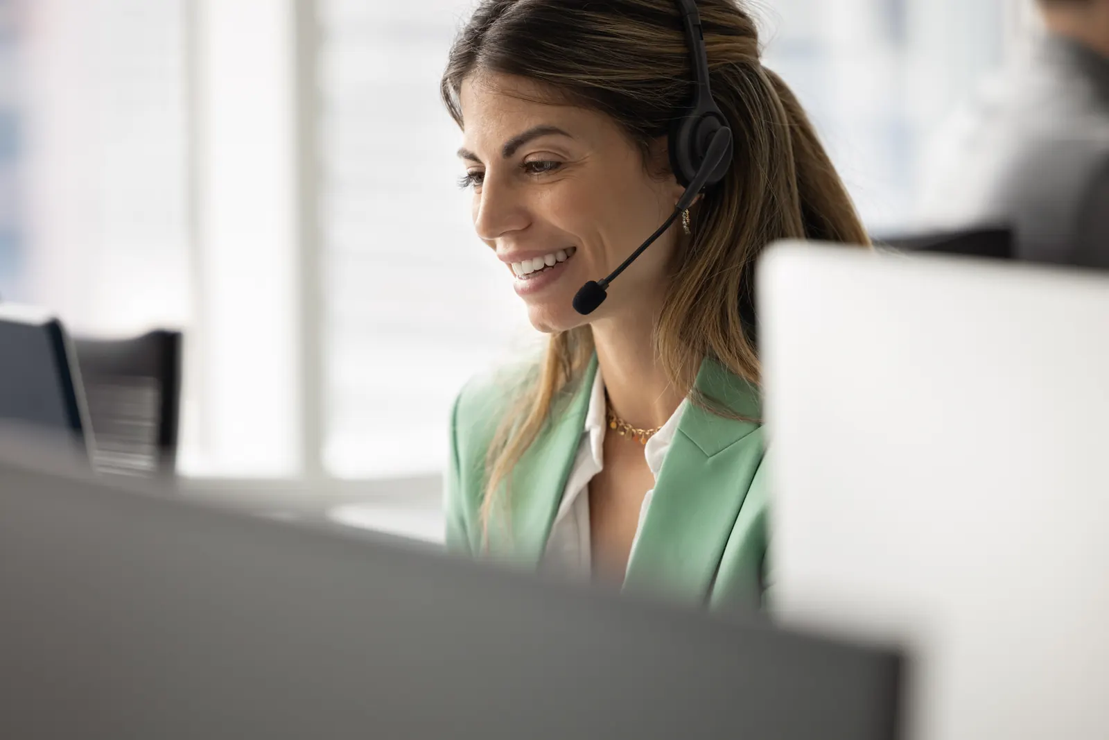 A customer service representative listening through a headset at her computer