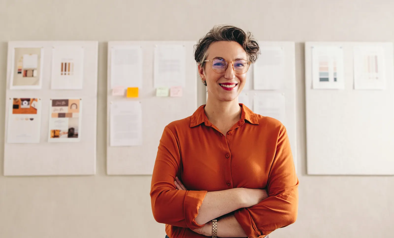 Professional in a warm orange shirt standing beside a workshop planning wall