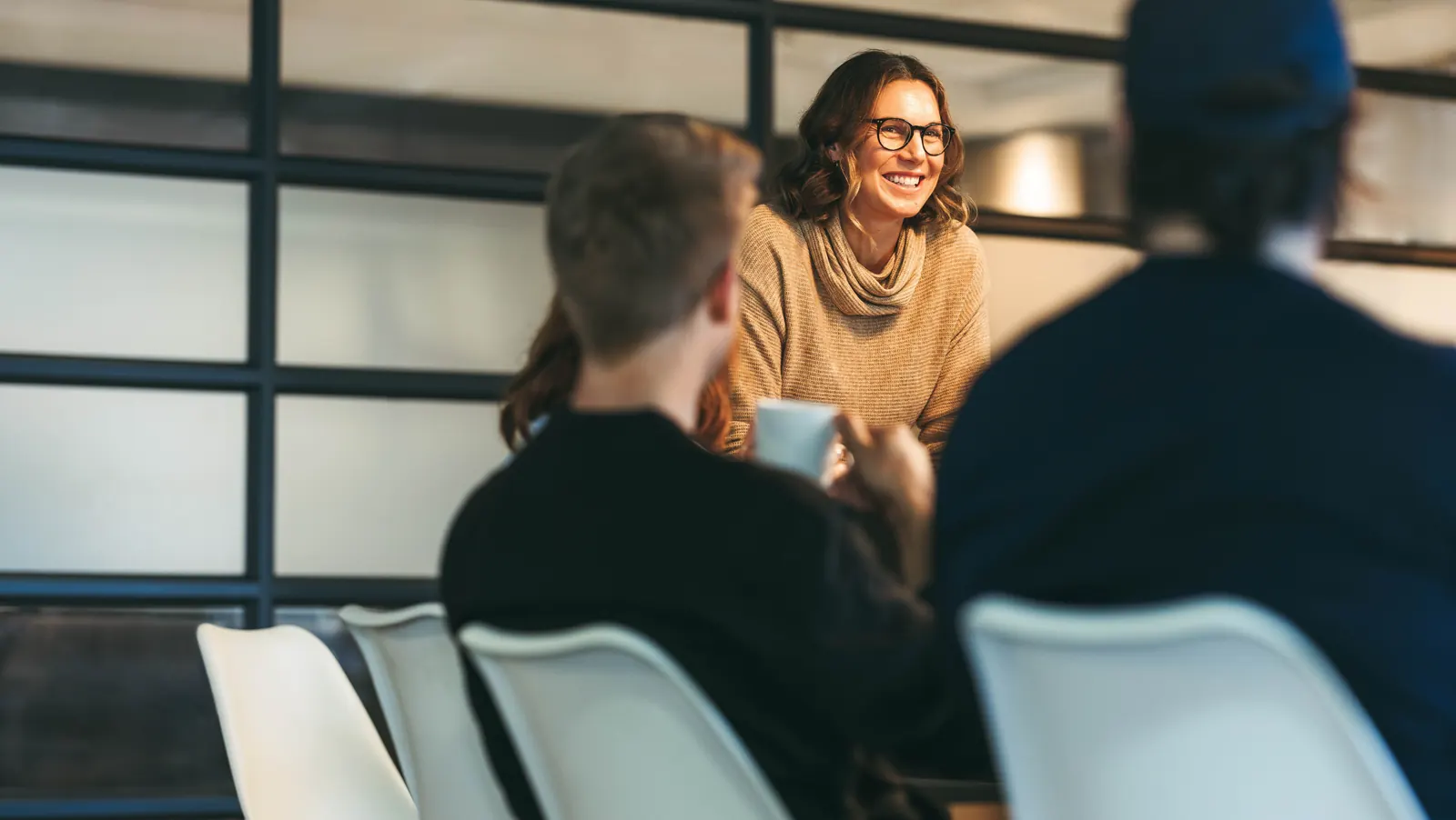 A facilitator discussing requirements with two colleagues across a table