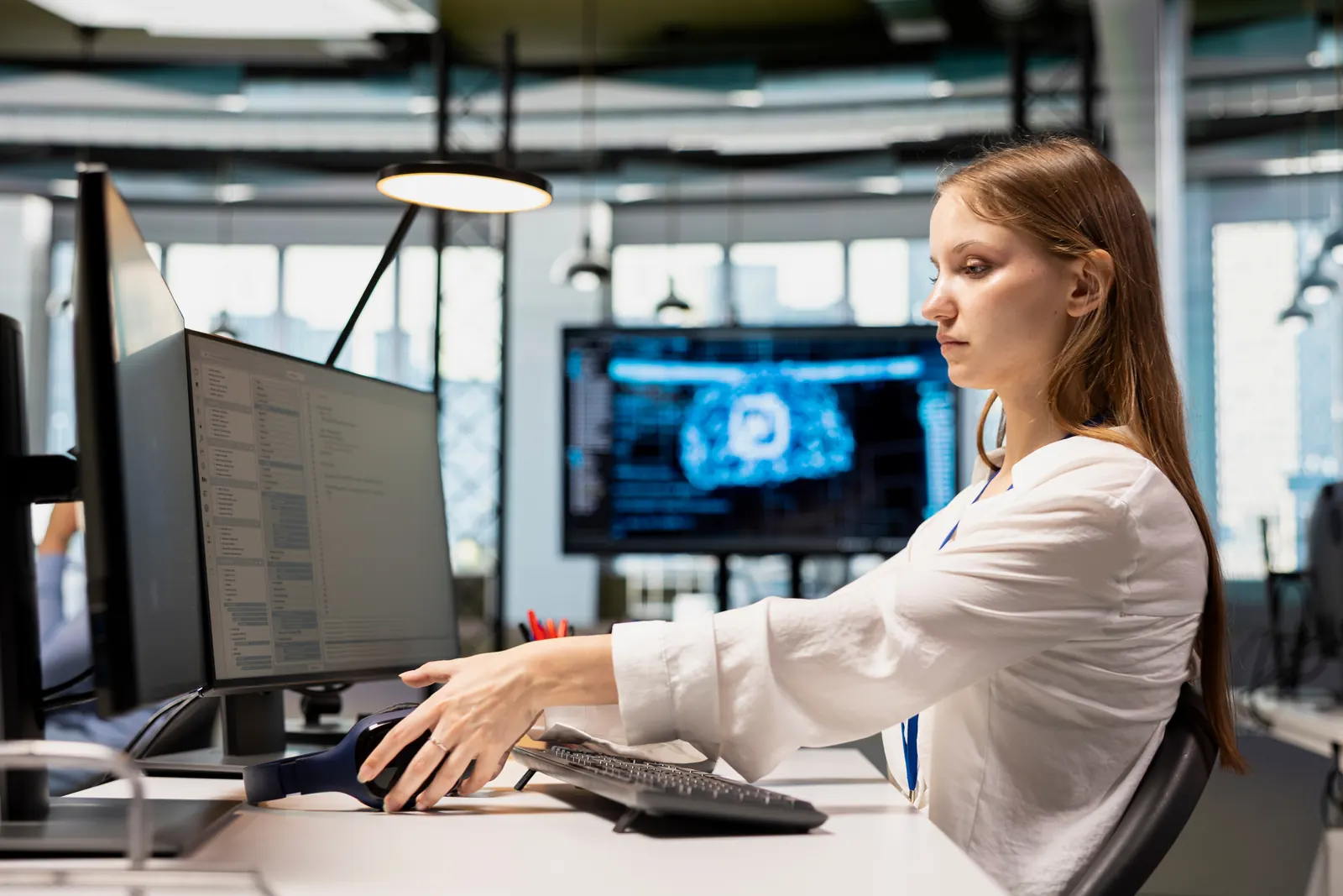 A technology specialist reviewing information on two desktop displays