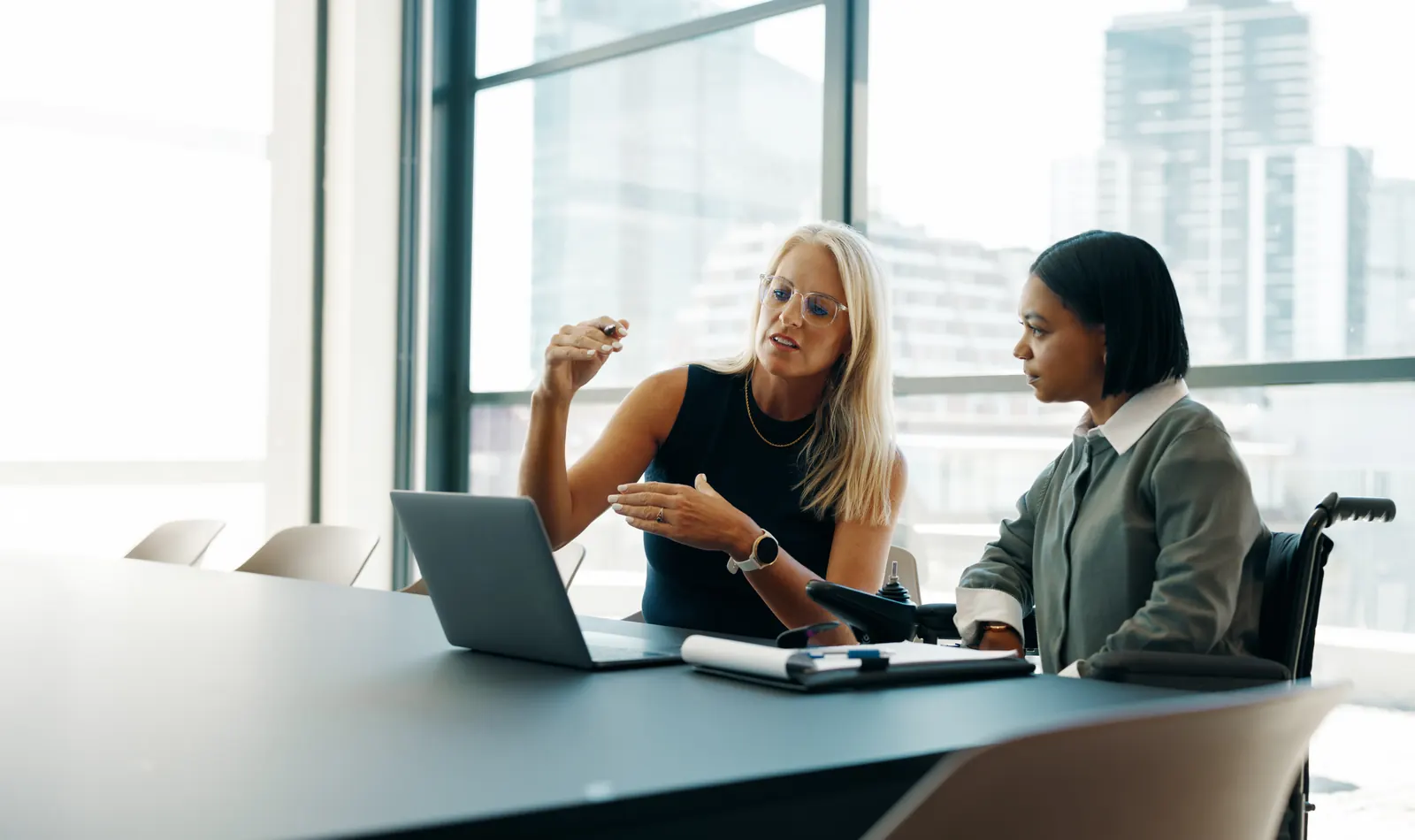 Two colleagues reviewing information together at a desk in a bright office