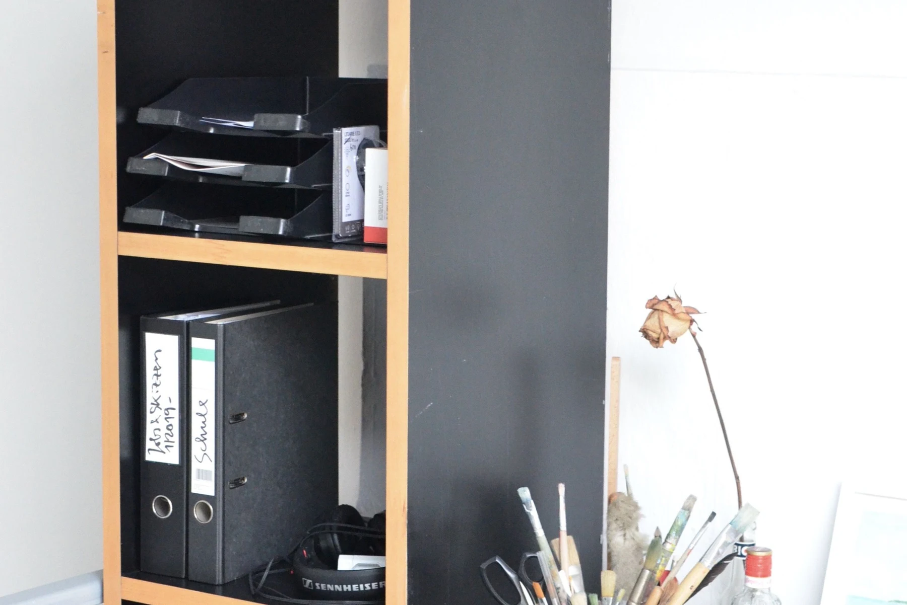An office shelf holding folders beside a wooden working desk