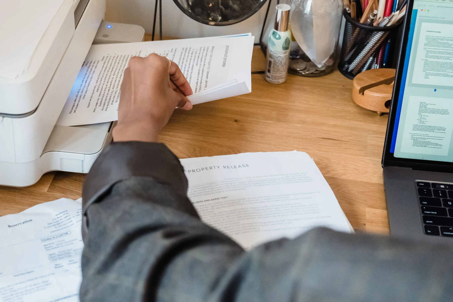 A colleague checking printed documents beside a laptop and printer