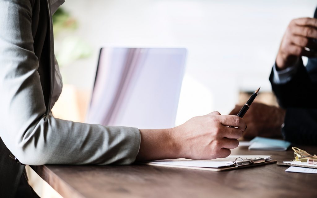 A woman handing a pen to a client to sign a document during a business meeting