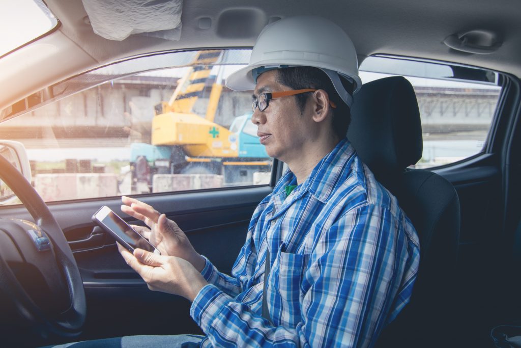 A field staff employee inspecting the optimized and planned routes on a mobile device while in a work vehicle